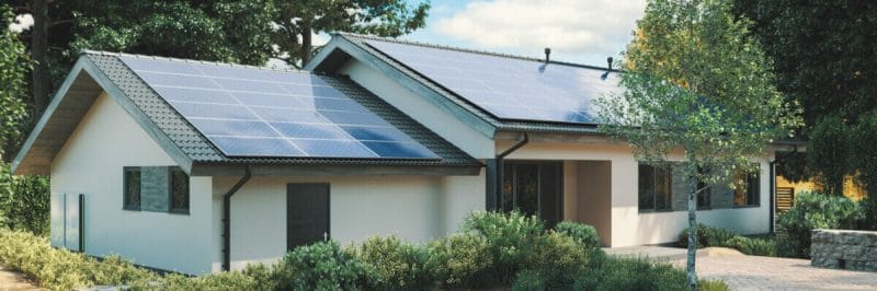 Modern single storey house with solar panels and wall battery for energy storage.